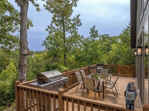 An outdoor deck with a grill, dining table, chairs, and a decorative owl statue. - On The Rocks by Innsbrook Vacations! (Innsbrook)