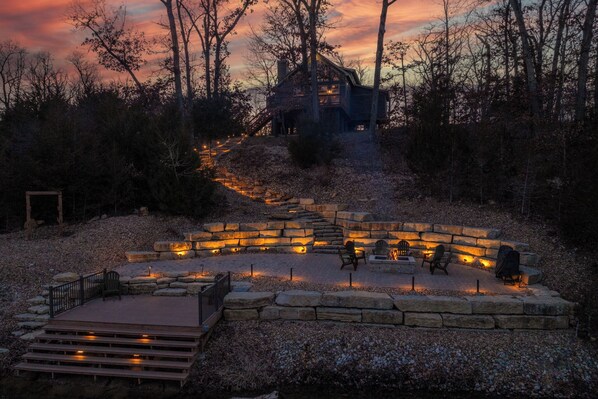 A stone deck with outdoor seating and a staircase leading to a wooden cabin. - On The Rocks by Innsbrook Vacations! (Innsbrook)