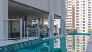 A swimming pool with glass railings, a view of high-rise buildings, and a clear sky.