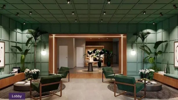 A lobby with a green color scheme, featuring a reception desk, two green armchairs, and a central table with plants.