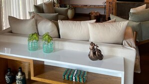A cozy living room with a wooden ceiling, a fireplace, a television, and a sofa with decorative pillows and vases. - Vila Tio Lé (Campos do Jordão)