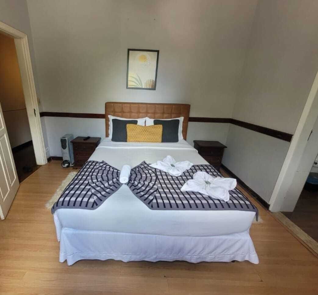 A neatly made bed with a checkered bedspread, pillows, and towels arranged on the bed.