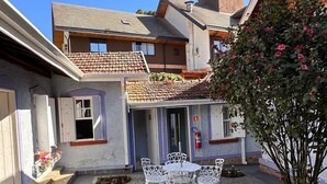 A courtyard with a patio table and chairs, surrounded by buildings with a mix of modern and traditional architecture. - Vila Tio Lé (Campos do Jordão)