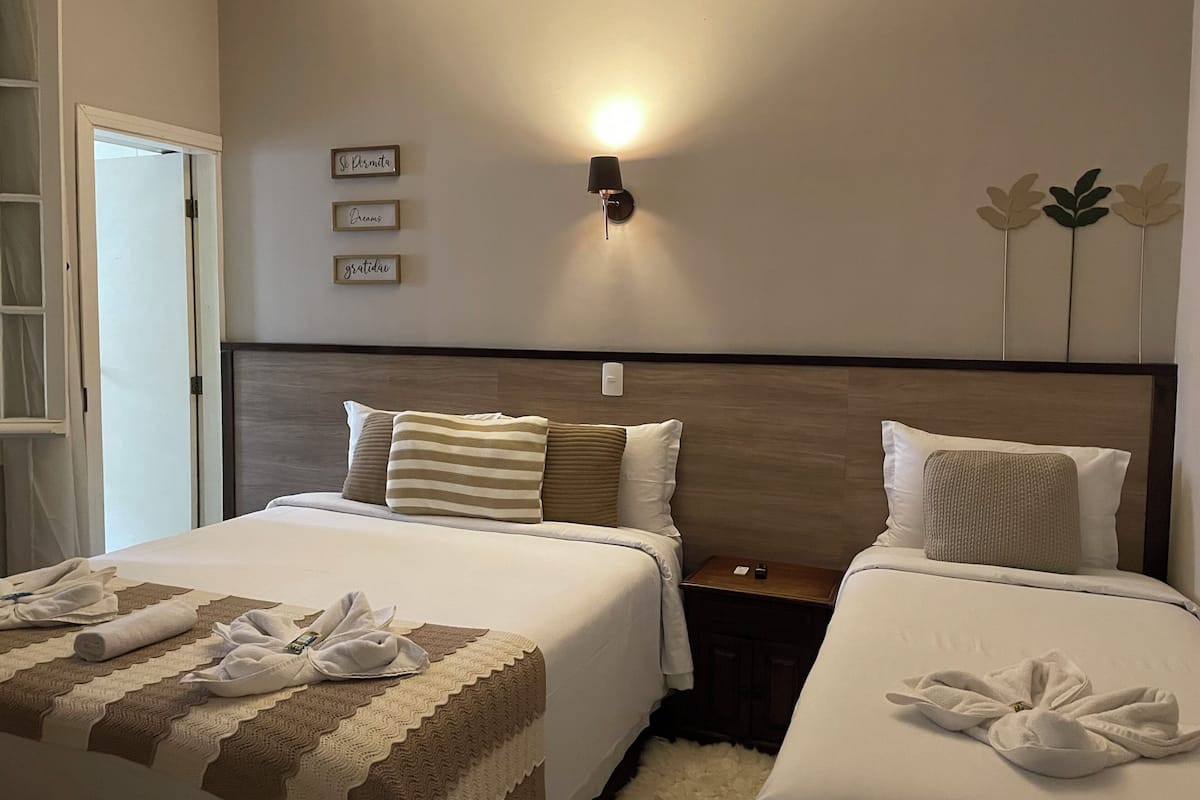 Una habitación de hotel con dos camas, una mesita de noche, una lámpara de pared y decoración en la pared.