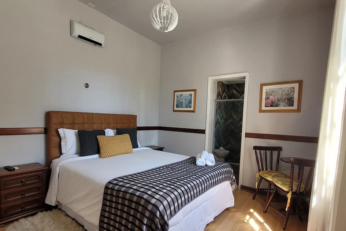 Un dormitorio ordenado con una cama grande, una mesita de noche de madera, una silla y una pequeña mesa.