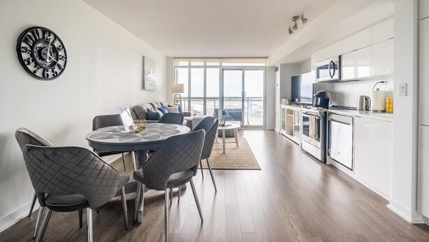 A modern apartment with a dining area, kitchen, and large windows offering a city view. - GLOBALSTAY. Bird's eye view of the lake 1bd+den in Downtown (Toronto/Canada)