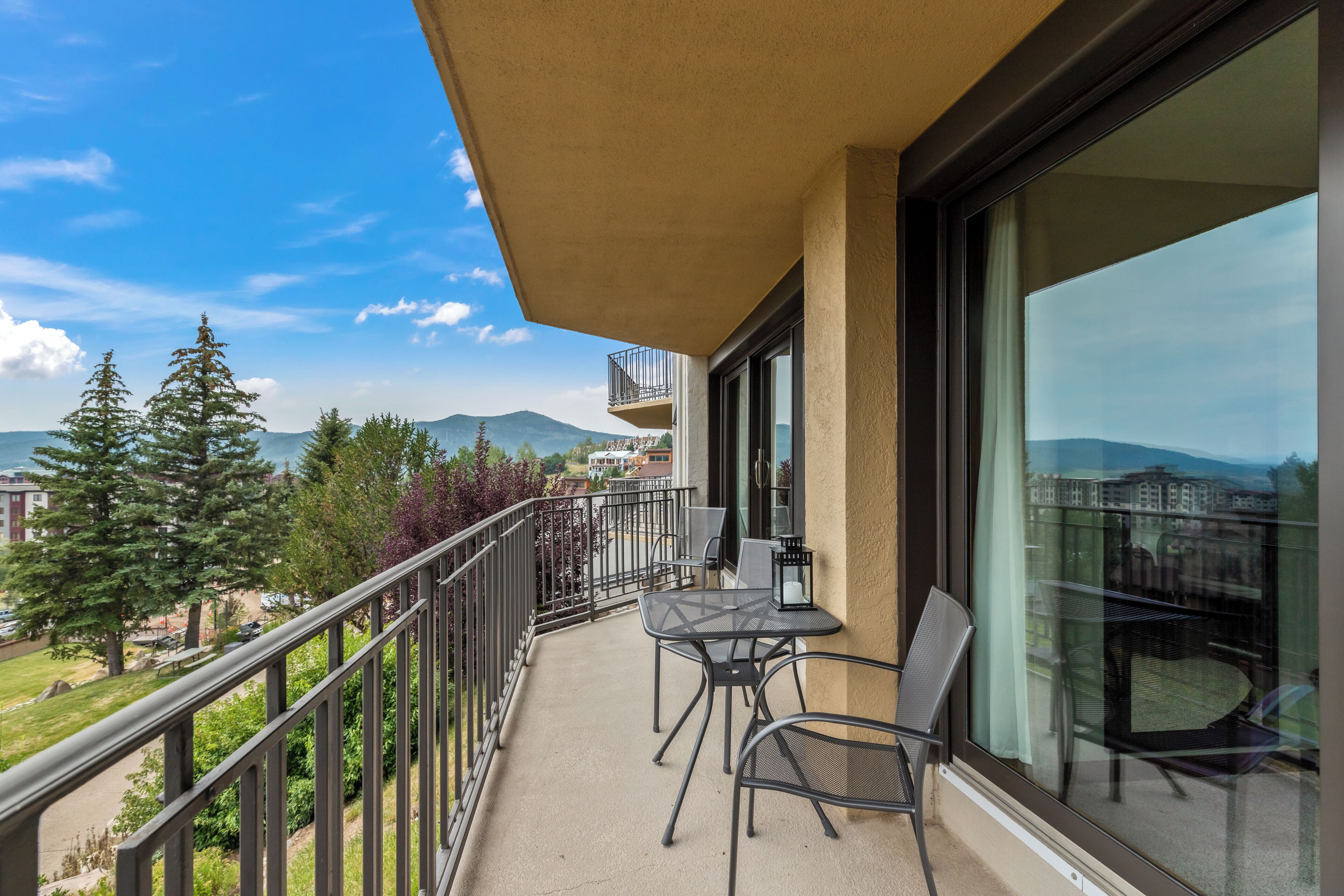 Ein Balkon mit Tisch und Stühlen, der einen malerischen Blick auf Bäume und Berge bietet.