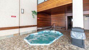 Un área de piscina con suelo de baldosas, techo de madera y un cubo de basura.