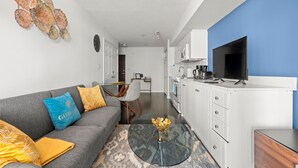 A modern living room with a grey sofa, a coffee table, and a TV on a stand.