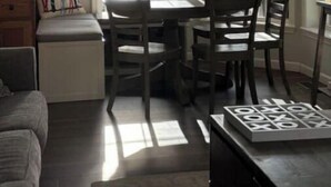 Un comedor con una mesa, sillas, una lámpara colgante y ventanas amplias con vistas.