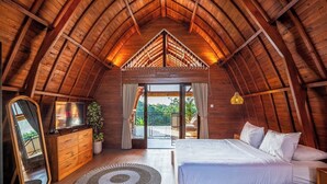 A cozy attic bedroom with a wooden ceiling, a bed, a dresser, a mirror, and a view of the outdoors. - Modern Villa with Gym and rare Jungle view in Canggu (Tibubeneng)
