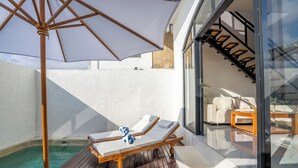 A sunlit outdoor area with a wooden deck, a pool, and a lounge chair with a towel. - Modern Villa with Gym and rare Jungle view in Canggu (Tibubeneng)
