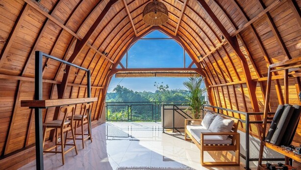 An attic room with a wooden ceiling, a sofa, a chair, and a table with dumbbells. - Modern Villa with Gym and rare Jungle view in Canggu (Tibubeneng)