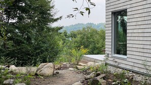 A modern building with a large window, surrounded by a natural landscape with trees and rocks. - Chalet des Sentiers - An architectural experience at Lac Fidèle, Entrelacs  (Entrelacs)
