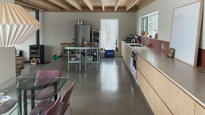 A modern kitchen with wooden beams, a glass dining table, and a large window. - Chalet des Sentiers - An architectural experience at Lac Fidèle, Entrelacs  (Entrelacs)