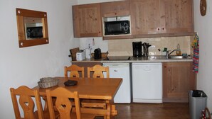 Una cocina compacta con armarios de madera, un microondas, un tostador y un lavabo.