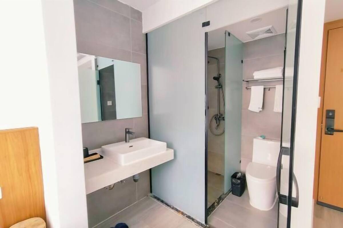 Une salle de bain moderne avec une douche à parois de verre, un lavabo blanc et des toilettes.