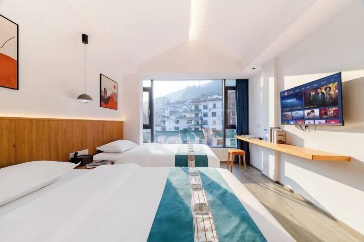 Une chambre d’hôtel avec deux lits, un bureau, une télévision et une vue sur la ville.