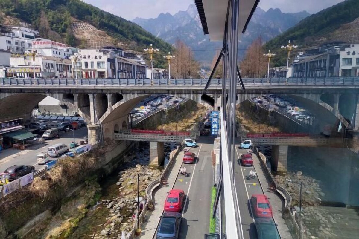 Un puente con vehículos a ambos lados, un río abajo y edificios al fondo.