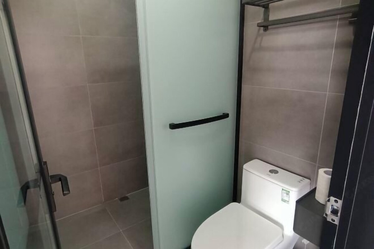 Un baño con inodoro, cabina de ducha de vidrio y barra para toallas.