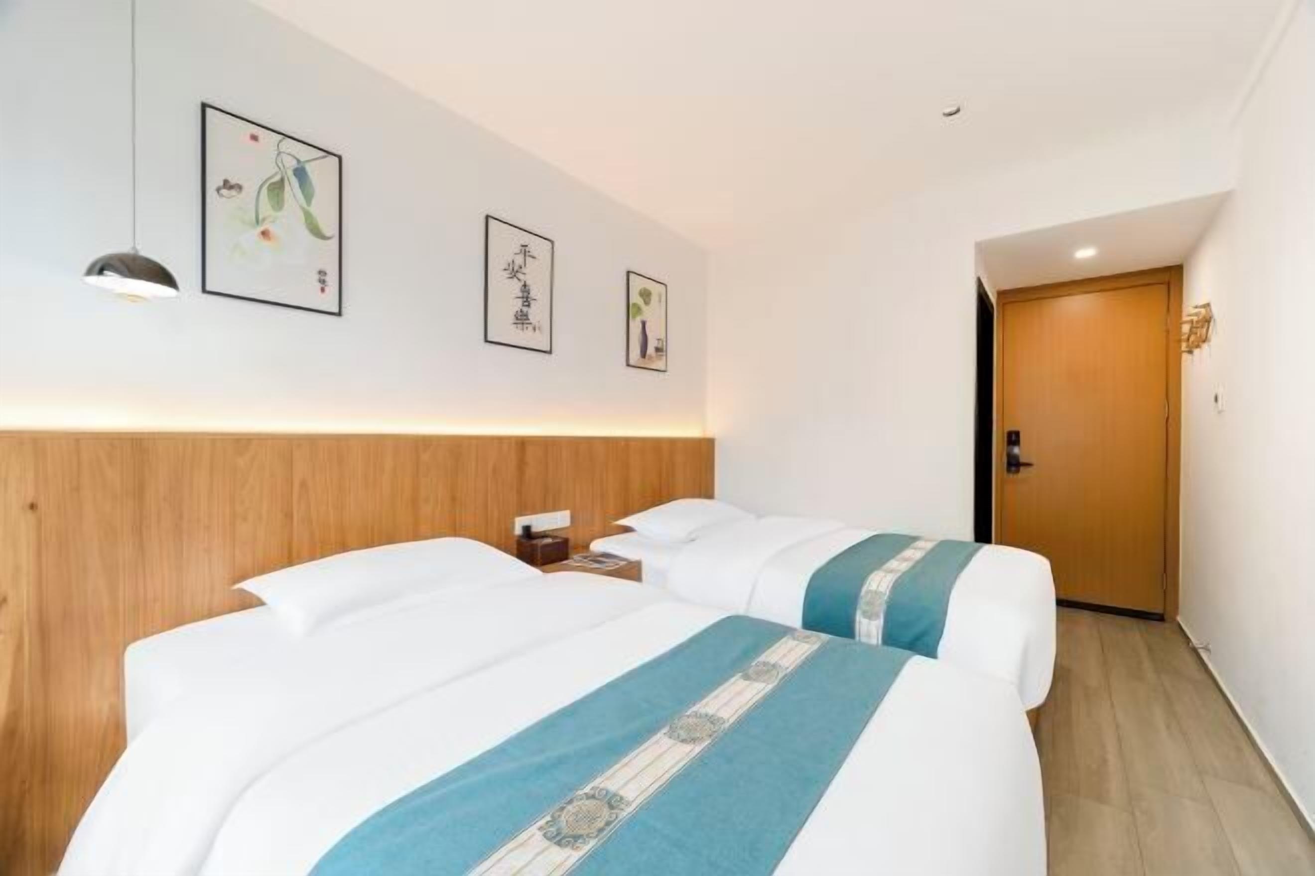 A hotel room with two beds, a wooden headboard, a nightstand, and wall art.