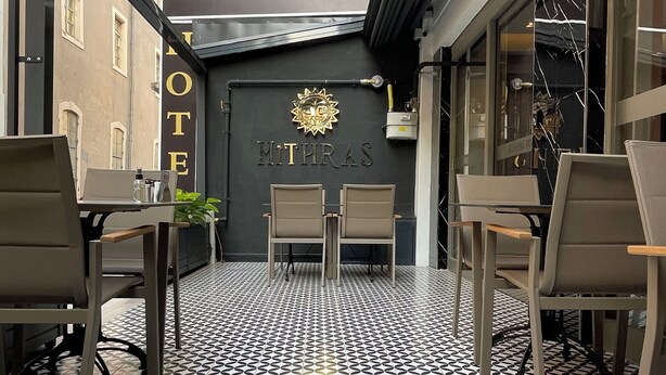 L’entrée de l’hôtel-café Mithras, avec son sol à motifs géométriques et une enseigne au-dessus de la porte.