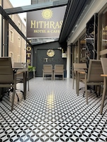 La entrada del Hotel & Cafe Mithras, con un suelo de diseño geométrico y un cartel sobre la puerta.