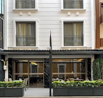 A hotel with a modern facade, large windows, and a well-maintained outdoor seating area.