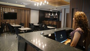 Un espace bar moderne doté d’un long comptoir, de plusieurs types de sièges et d’un téléviseur fixé au mur.