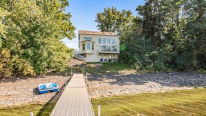 Een tweelaags huis met een balkon, een steiger en een boot.