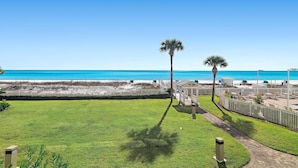A beachfront property with a clear view of the ocean, a well-maintained lawn, and a pathway leading to a gazebo. - Sterling Sands 103 (Destin)