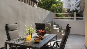 A patio with a table set for breakfast, including a bowl of fruit, cookies, and a glass of orange juice. - Casa Amarillo is the perfect place for your holidays (Chania)