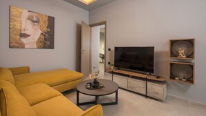 A modern living room with a sofa, a coffee table, a flat-screen TV, and decorative items. - Casa Amarillo is the perfect place for your holidays (Chania)