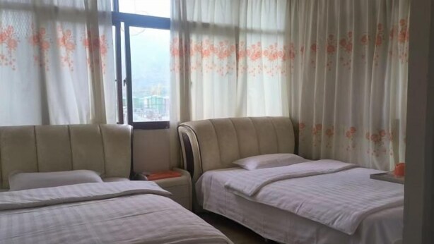 A hotel room with two beds, a window, and curtains. - Jiangling Inn (Songpan)