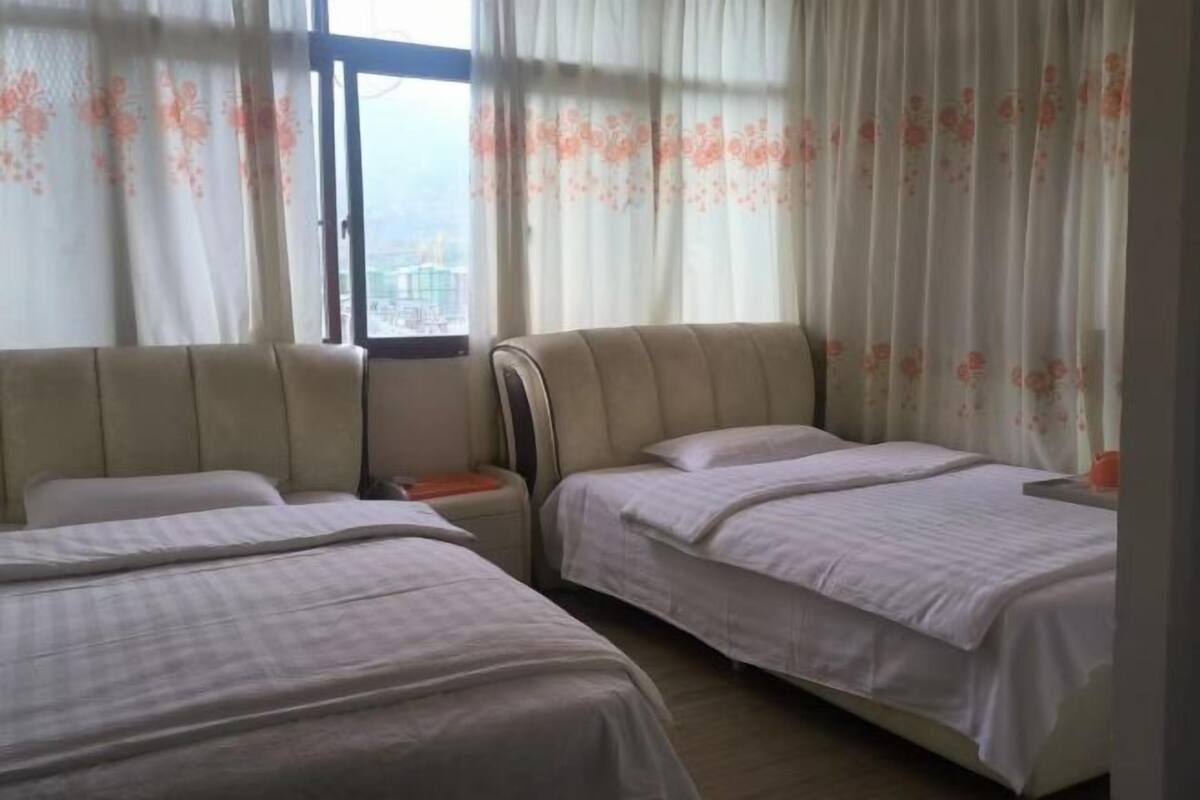 Ein Hotelzimmer mit zwei Betten, einem Fenster und Vorhängen.