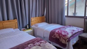 Une chambre avec deux lits, une fenêtre et des rideaux.