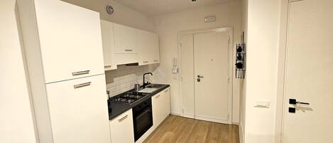 A compact kitchen with white cabinets, a black countertop, and a stove.