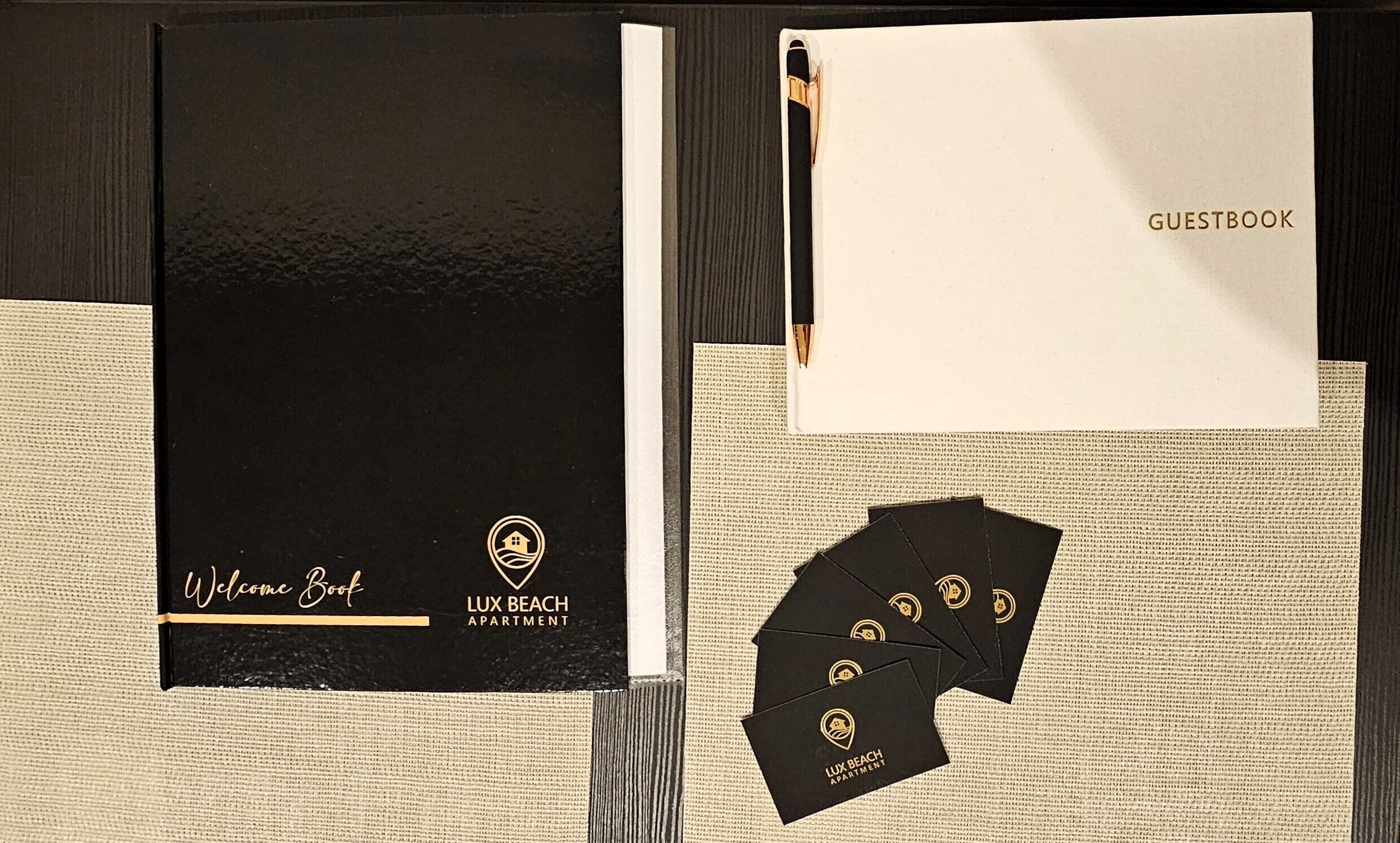 A guestbook, a welcome booklet, and a pen on a textured surface.