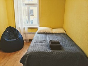 A small room with a bed, a bean bag chair, and a window with a view of buildings. - Peaceful studio with desk & free parking (Tallinn)