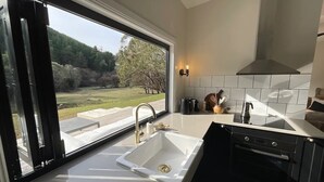 Una cocina moderna con un ventanal amplio, encimeras blancas y un horno empotrado.