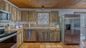 A kitchen with wooden cabinets, a stainless steel refrigerator, a dishwasher, and a microwave.