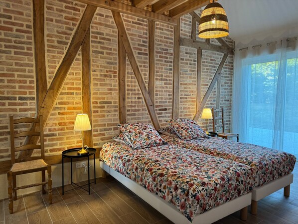 Une chambre à coucher avec un grand lit, des poutres en bois, des murs en briques et une fenêtre avec des rideaux.