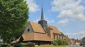 A church with a tall steeple, a brick facade, and a small bell tower.