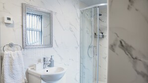 A modern bathroom with a white marble sink, a glass shower enclosure, and a large mirror. - 2Bed Apartment Near City Centre (Sleeps 4, with free parking) (Coventry)
