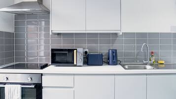 A modern kitchen with a microwave, toaster, kettle, and a sink with a faucet.