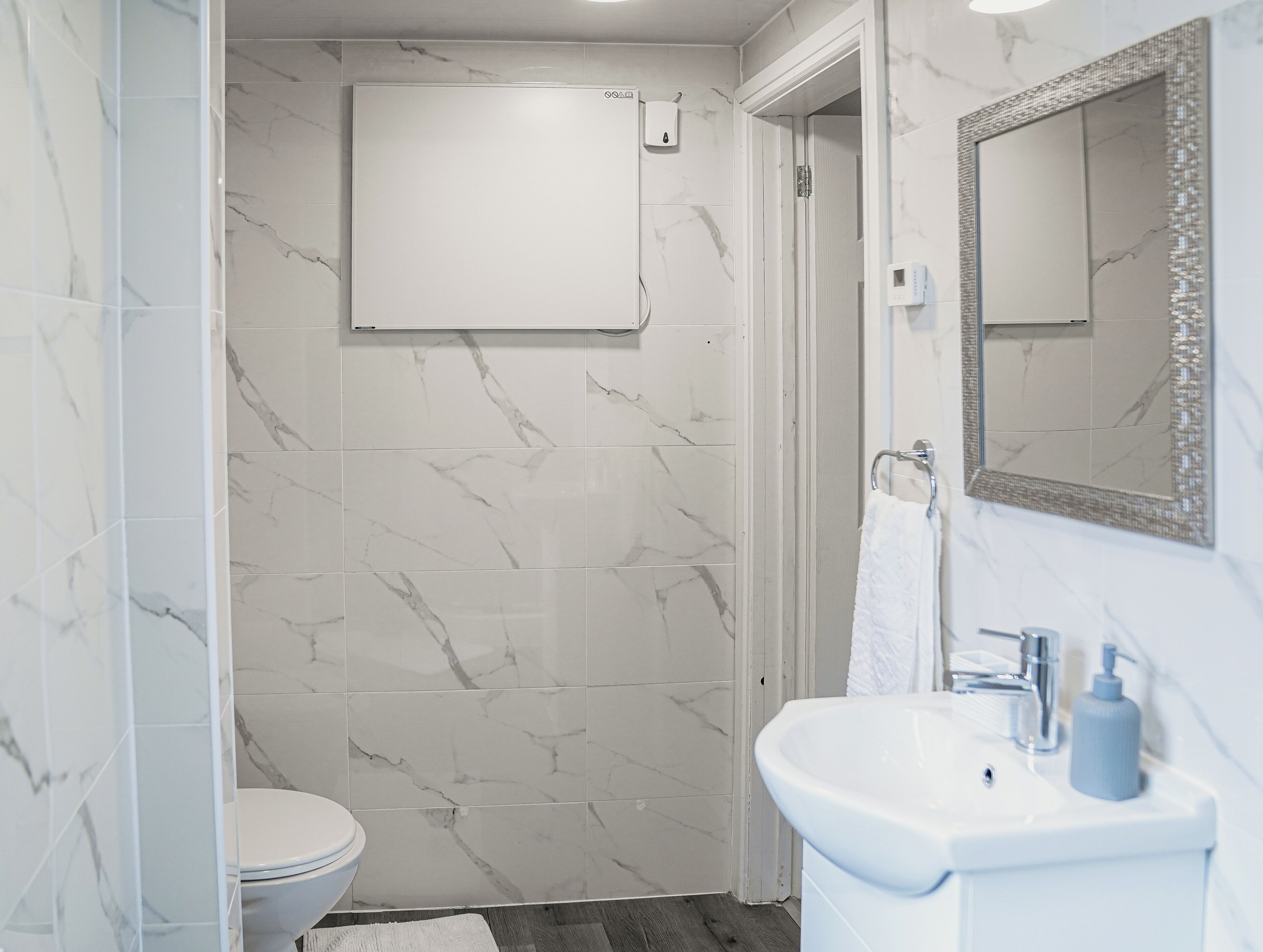 A bathroom with a toilet, a shower, and a sink with a mirror.