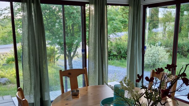Een houten eettafel met stoelen, een vaas met bloemen en een blauwgroene dienblad.