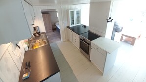 Een kleine keuken met witte kastjes, een zwart aanrecht en een inbouwoven.