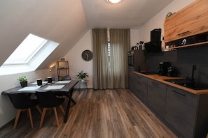 A modern kitchen with a skylight, wooden dining table, and dark cabinetry.