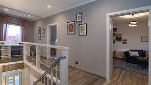 Ein modernes Interieur mit Treppe, Schreibtisch und Wohnbereich inklusive Sofa und Heizkörper.